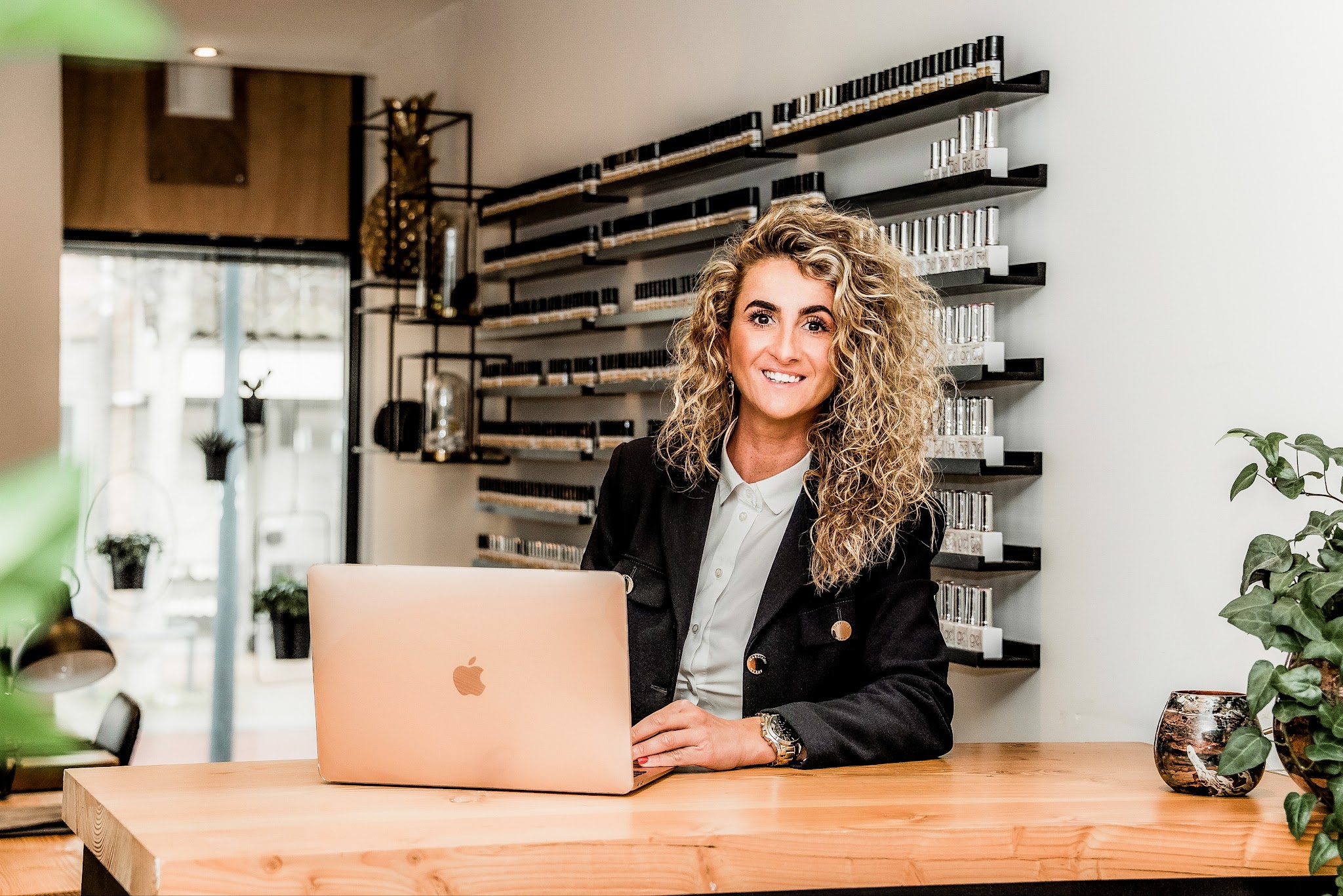 Aan de houten balie van de salon, met de wand vol nagellak erachter