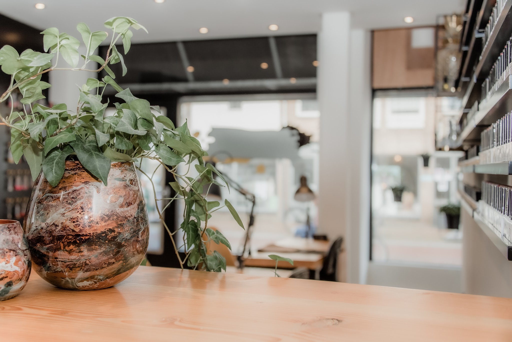 Plant in een koperen vaas op de houten balie, met de werktafels bij het raam